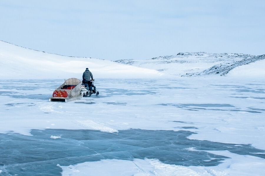 A person rides a sled across an ice sheet in the Canadian Arctic.