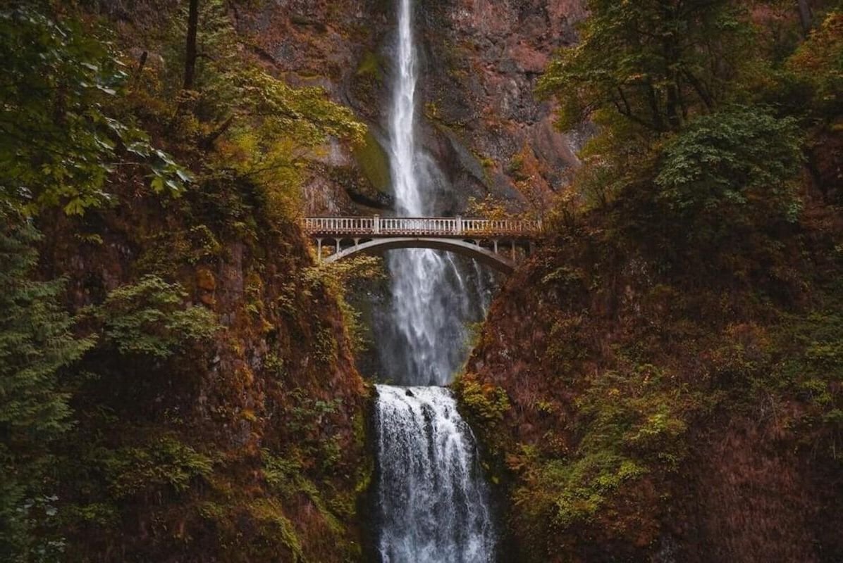 tall waterfall and bridge with fall foliage colors on a gloomy day