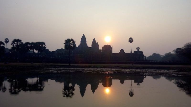 View of Angkor Wat at sunrise with the temple skyline reflected in the pond
