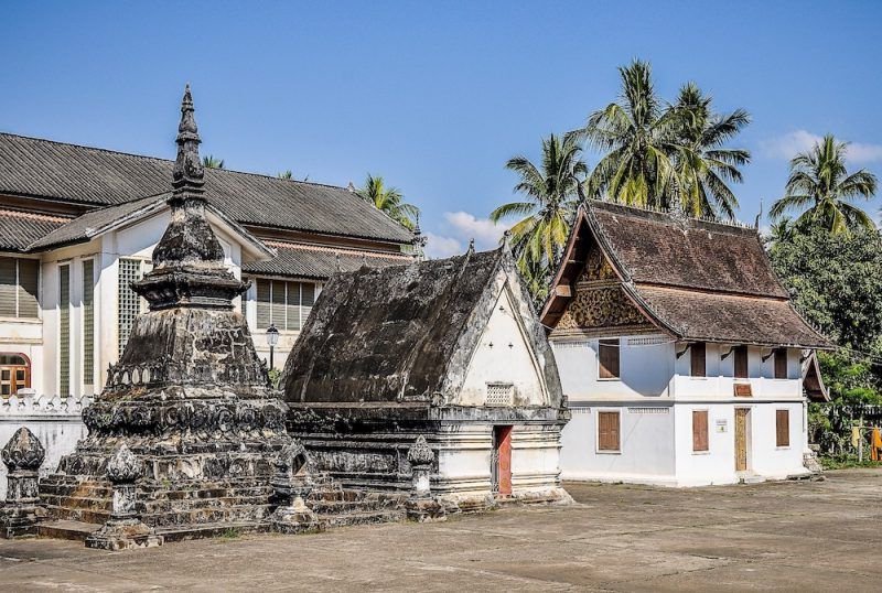 A view of a temple in Laos with stone carvings and white buildings