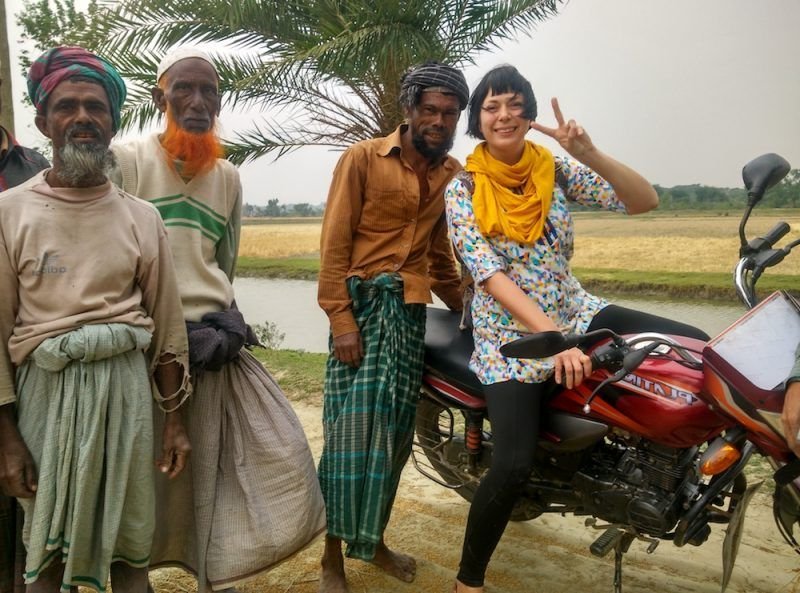 Alice on a motorbike with people in Bangladesh also posing with her