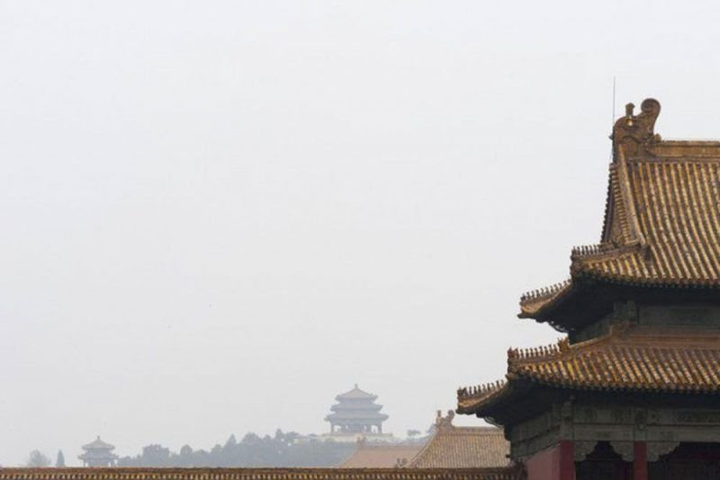 View of the rooftops of the Forbidden city in China with foggy sky and other pagodas visible