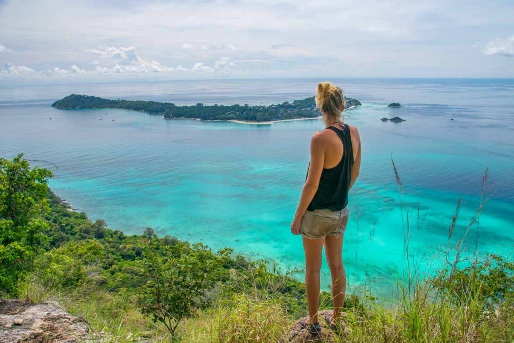 Blond woman in shorts in front of a blue sea in Thailand